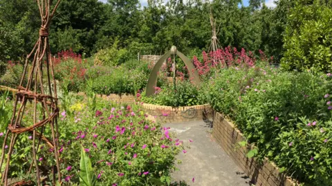 Karen Dobson The garden, which has paths running through planters filled with colourful flowers and trees.