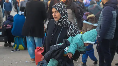 Getty Images Palestinians wait to be allowed to return to their homes in northern Gaza amid a ceasefire between Israel and Hamas after they were displaced to the south with Israel's order during the war. The Palestinians wait for the army to be withdrawn in order to allow them to cross the Netzarim checkpoint separating the north and south sides of the Gaza Strip. (Photo credit should read Ramez Habb