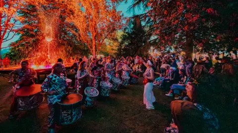 Nathan Roach/Shindig Festival Drummers dancing behind a lit up fountain in front of a large crowd of people