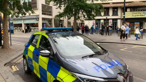 BBC Police car parked outside of shops