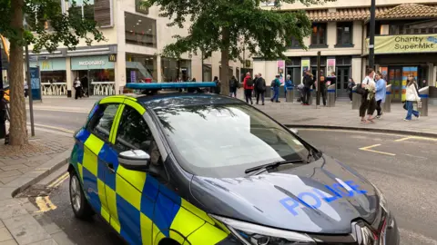 Police car parked outside of shops