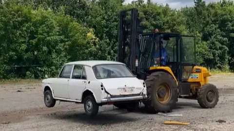 Car being carried on a forklift tuck