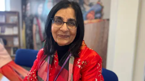 A woman with dark hair and glasses smiling