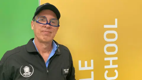 BBC/ James Grant Closeup of man wearing a space suit and upside down glasses