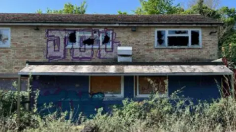 Greater Cambridge Planning The abandoned former Comfort Cafe. It is a two-storey building with broken and boarded-up windows and graffiti.