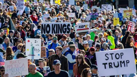 Getty Images 'No Kings' protests against Trump were held across the US last year. Protesters are seen carrying anti-Trump signs