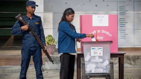 Reuters A woman casts her vote as a security officer stands guard at a polling station
