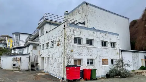 An alternative side angle shows dirty, cracked exterior walls and overgrown weeds around the building.