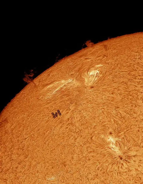 Tom Williams The Sun featuring the silhouette of the International Space Station (ISS) transiting the eastern solar limb