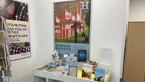 Amy Holmes/BBC A picture of various books and mugs and souvenirs inside the Bedford cultural hub on display.