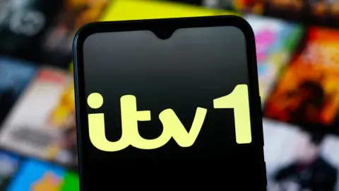 Getty Images Mobile phone with an ITV 1 logo in black and yellow on the screen and blurred images of a streaming service in the background