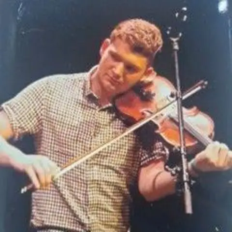 Police Scotland A man in a checked shirt plays the fiddle