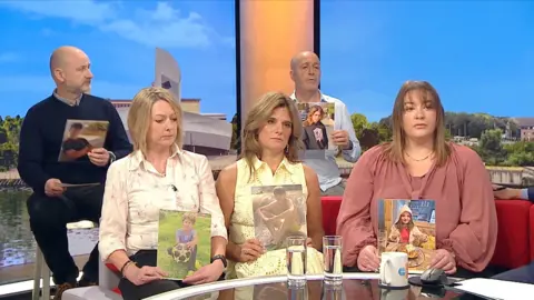 Parents sit with photographs of their children.