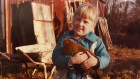 An old picture of young Claire holding a chicken.