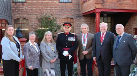 Charnwood Borough Council A line of men and women including the vice lord lieutenant of Leicestershire in a dark blue and red military style uniform