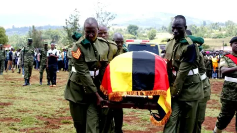 Peter Njoroge / BBC Um caixão coberto com uma bandeira de Uganda sendo carregado