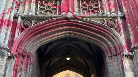 The archway of an old university building has been covered in red paint. 