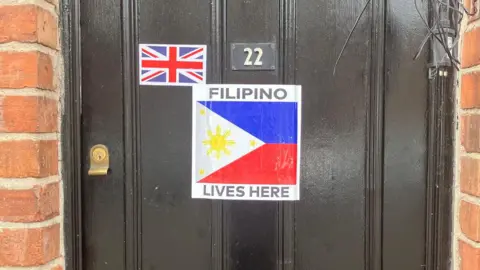 A black front door with a sticker saying Filipino lives here on it