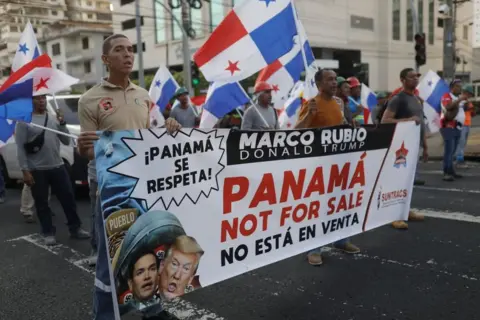 EPA protesters in Panama City, waving their national flag, protest against a visit by US State Secretary Marco Rubio. Reads a sign in English and Spanish: "Panama: not for sale", 