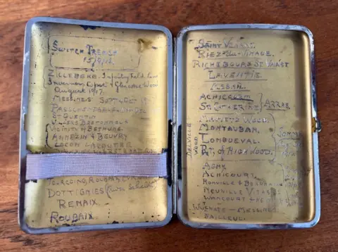 The inside of a cigarette case with a number of World War One battled etched into the metal