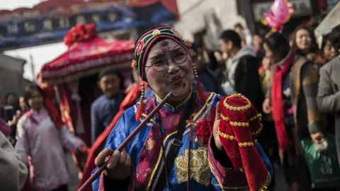 Getty Images Chinese woman dressed in traditional costume attends a wedding performance as part of the She Huo festival, to celebrate the Lunar New Year, marking the Year of the Dog, in Hancheng, Shaanxi province, on February 16, 2018