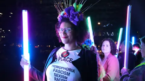 Women carrying illuminated poles