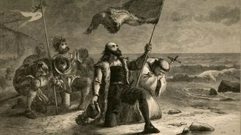 The Print Collector/Getty Images Black-and-white painting of Christopher Columbus arriving on a beach holding a flag in his left hand