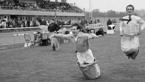 Historic England/John Laing Collection Three men take part in a sack race