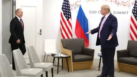 Getty Images Donald Trump stands on his sides with his hands spread apart, Vladimir Putin at a meeting at the G20 summit in Osaka, Japan in June 2019