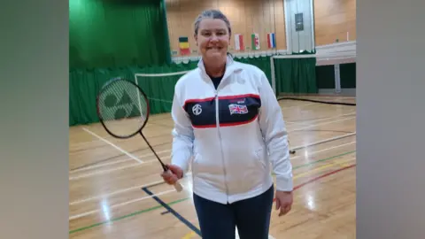 Lesley Miller holding a badminton racket and wearing her team Great Britain tracksuit.