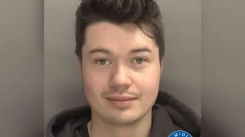 West Midlands Police A young man's face with short black hair and a deep hoodie against a gray background