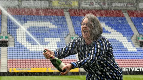 PA Media Ms Breen pops a champagne cork
