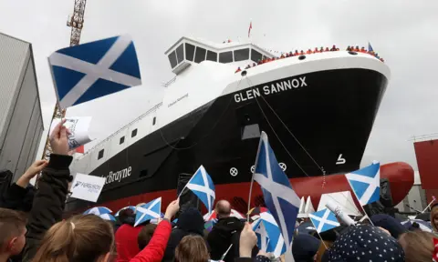 PA Media People question    saltires portion    watching a ample  red, achromatic  and achromatic  vessel  determination   down   the slipway.