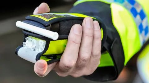 A police officer holds a breathaliser.