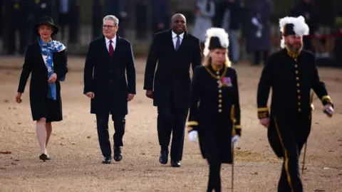 PA Media Prime Minister Keir Starmer walks in between David Lammy and Yvette Cooper along The Mall