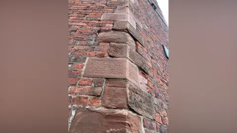 BBC/John Bowness Cornerstone bricks on one side of Dixons Chimney in Carlisle. Dixons Chimney is a red-brick structure and the cornerstone sections have larger bricks than the main structure.