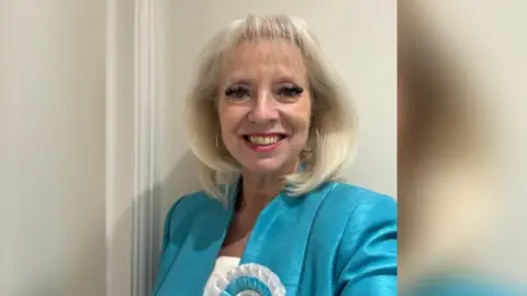 Reform UK Maxine Fothergill, the former Reform KCC councillor, pictured after being elected. She is wearing a blue suit and blue rosette. She has blonde hair.