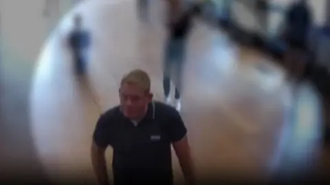 Thames Valley Police A CCTV image of Michael Jones at Blenheim Palace wearing a blue polo shirt.