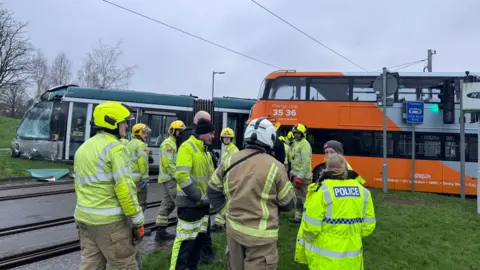 Nottinghamshire Fire and Rescue Service A damaged tram, off its rails, with a number of emergency workers standing in front