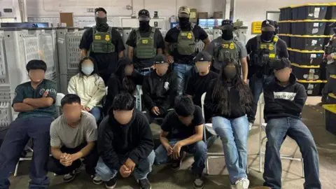 10 teenagers with their faces blurred to protect their identities sit in front of 5 federal immigration agents who also have their faces blurred. 
