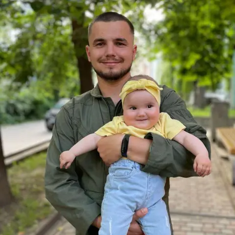 Maria Smeerechanska Ivan, 31, carrying her daughter Yaroslava