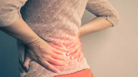 Getty Images Woman holding her back