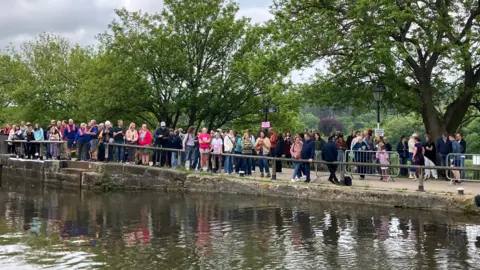 Olivia Richwald/BBC Crowds of people stand on the canalside