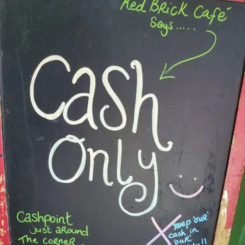 Hayley Mason Chalk board which reads - Red Brick Cafe says cash only, cashpoint just around the corner, keep cash in our society.