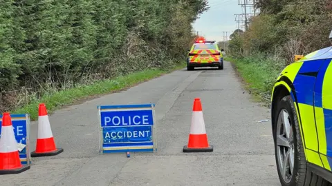 Some cones, a sign reading "police accident" sat in the road, and a police car about 40ft away flocking the road.