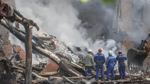 Emergency personnel work at the site of an apartment building damaged during a Russian missile and drone strike
