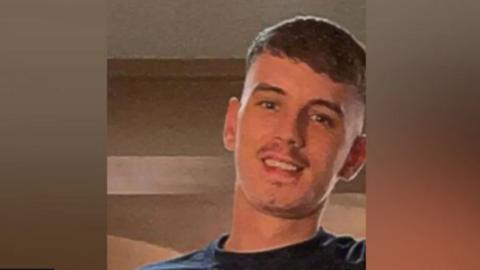 A family picture of Callum Norris, cropped closely to his face. He is smiling and looking slightly down into the camera. 