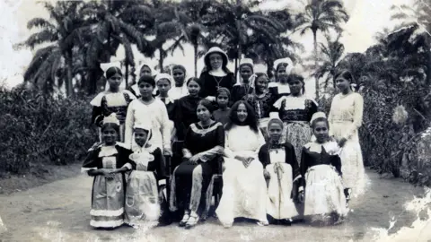 Eve Blouin A black-and-white picture of a group of girls and a nun at the Order of Saint Joseph Cluny convent posing for a picture.