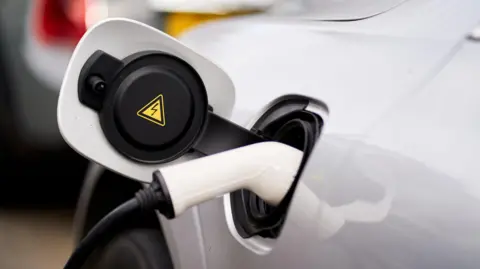 A white car being charged at an EV charging point.