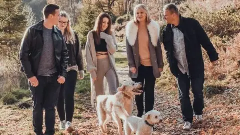 Michelle Chambers A family of three grown up children with their parents and two dogs going for a walk
